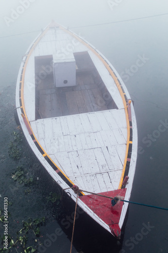 Pink boats in the water of the Ganges river during a densely foggy morning