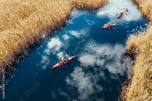 Foto Group of people in kayaks among reeds on the autumn river.