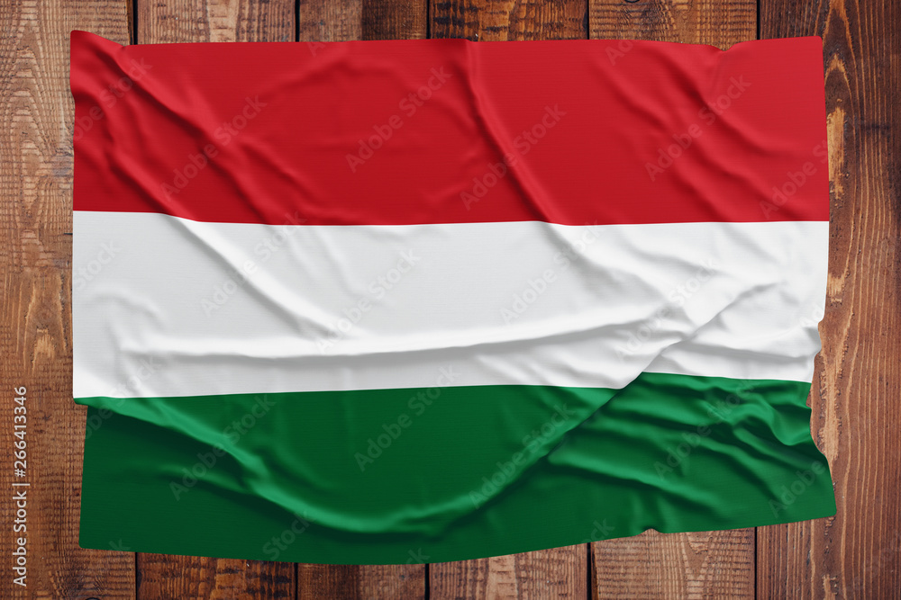Fototapeta premium Flag of Hungary on a wooden table background. Wrinkled Hungarian flag top view.