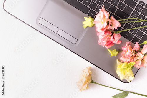White table with laptop and flowers. Freelancer workspace.