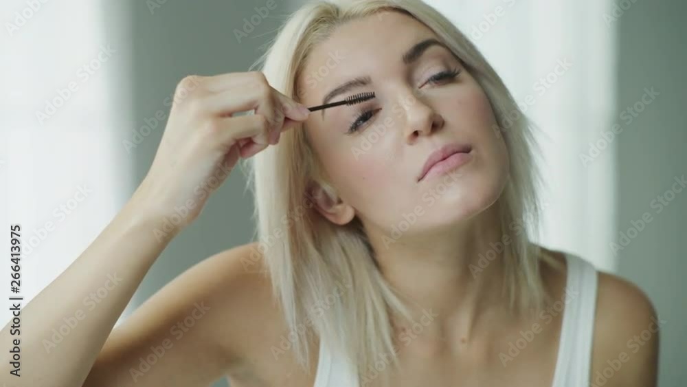 Close up of woman with blonde hair applying mascara in mirror / Cedar Hills, Utah, United States Close up of woman with blonde hair applying mascara in mirror / Cedar Hills, Utah, United States