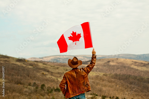 A man in a cowboy hat take canadian flag