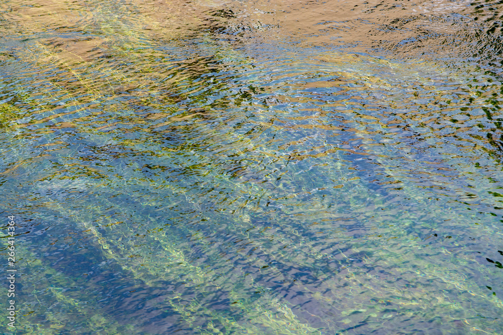 Background with clear green flow water of Sorgue river in Provence, France