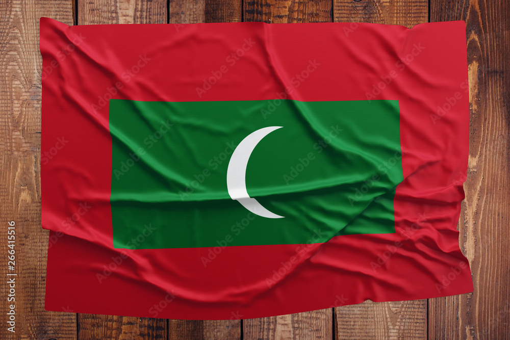 Flag of Maldives on a wooden table background. Wrinkled Maldivan flag top view.