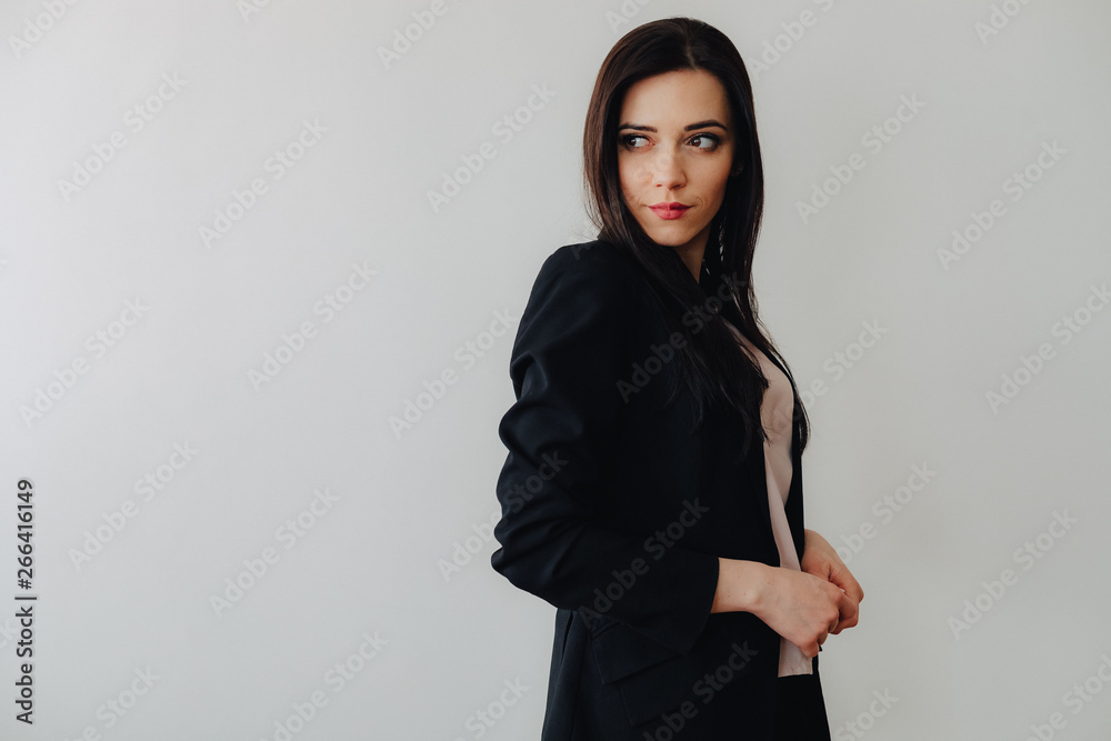 Young attractive emotional girl in business-style clothes on a plain white background in an office or audience