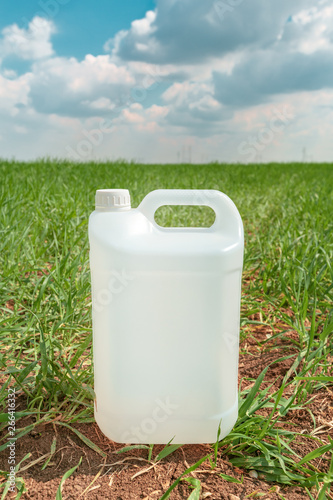 Fotografie Blank pesticide jug container mock up in wheatgrass field