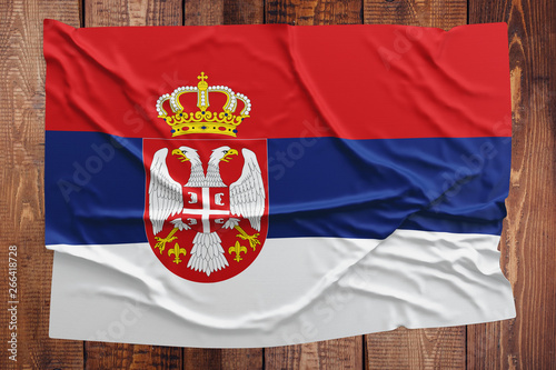 Flag of Serbia on a wooden table background. Wrinkled Serbian flag top view.