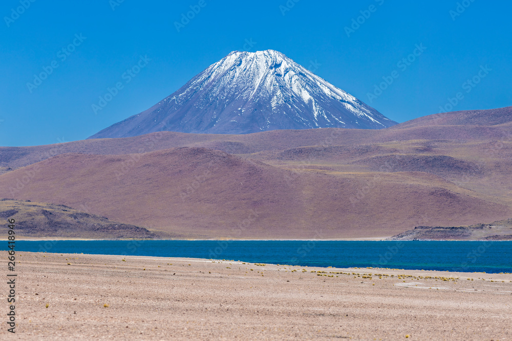 Chiliques volcano mountain over Miscanti lagoon blue waters and on the right the Cordon de Puntas Negras (Puntas Negras Mountain Range). An awe Andean Altiplano idyllic scenery inside Andes Mountains