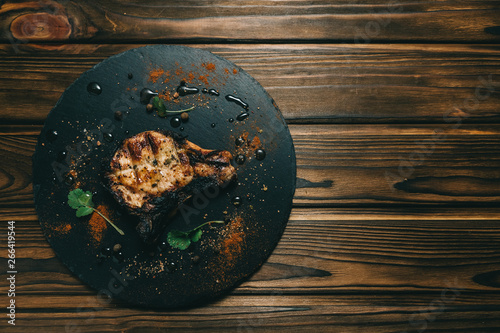 Pork bone steak on a wooden background with honey. Board slate. kenza, pepper photo