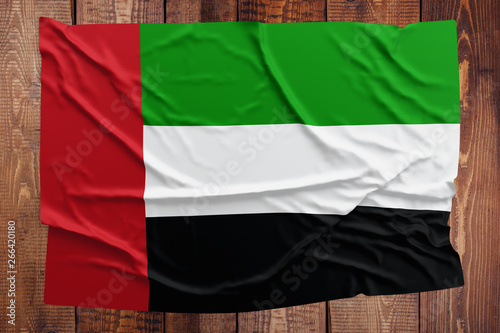 Flag of United Arab Emirates on a wooden table background. Wrinkled flag top view.
