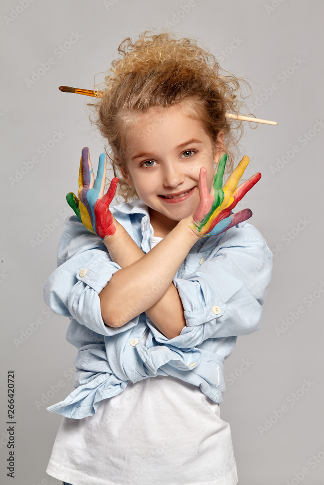 Beautiful little girl with a painted hands is posing on a gray background. Beautiful little girl with a painted hands is posing on a gray background.