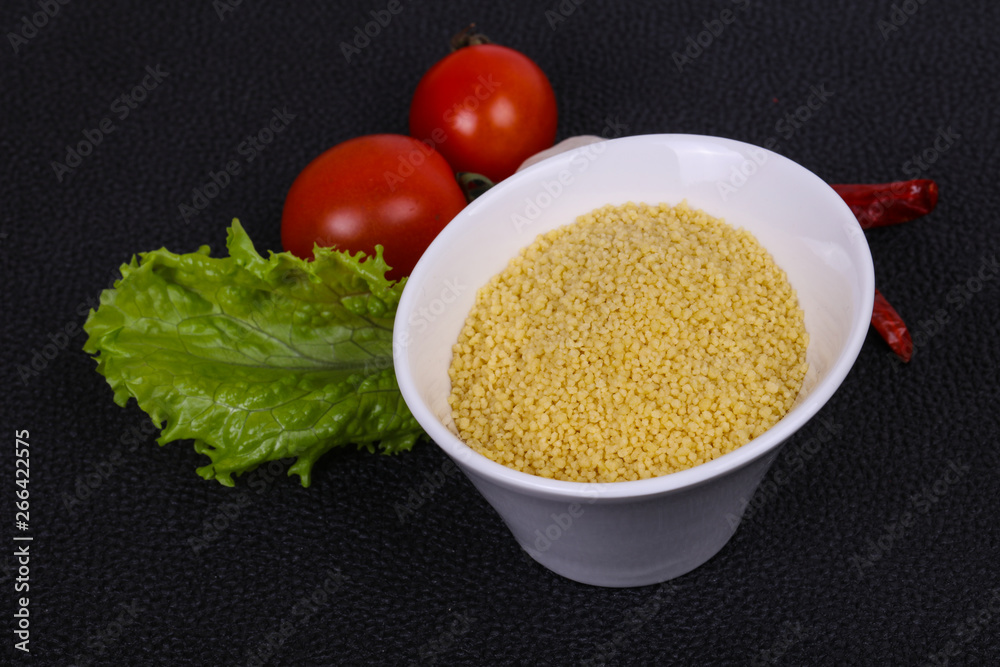 Raw couscous in the bowl served salad leaves, tomato and pepper Raw couscous in the bowl served salad leaves, tomato and pepper