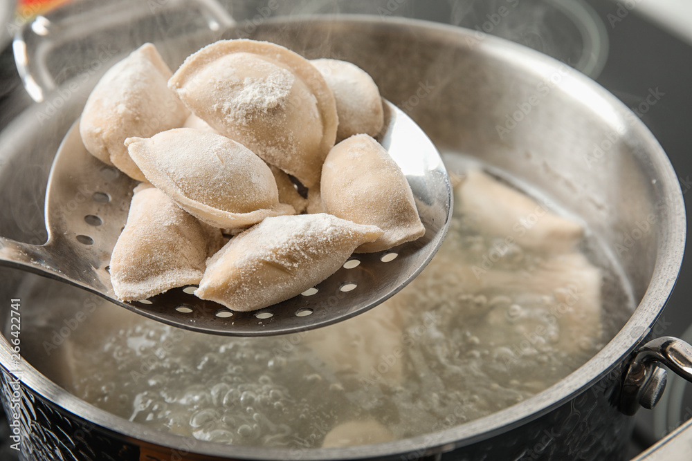 Closeup of dumplings on skimmer over stewpan with boiling water. Home cooking Closeup of dumplings on skimmer over stewpan with boiling water. Home cooking
