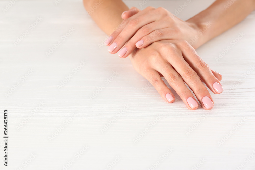 Closeup view of woman with beautiful hands at white wooden table, space for text. Spa treatment