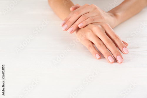 Closeup view of woman with beautiful hands at white wooden table  space for text. Spa treatment