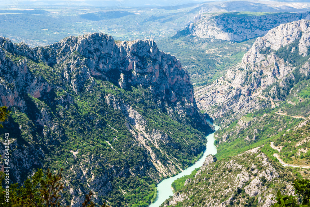 View over a mountainous landscape with high pikes and stony slopes down to the valley of Verdon River in France in summer.                                     Gorges du Verdon.