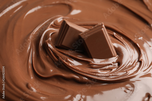 Sweet tasty chocolate cream with pieces as background, closeup