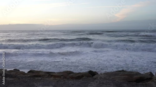 Ocean waves crashing on rocks close to the shore, late in a summer day. In Vagueira, Portugal. With copy space.