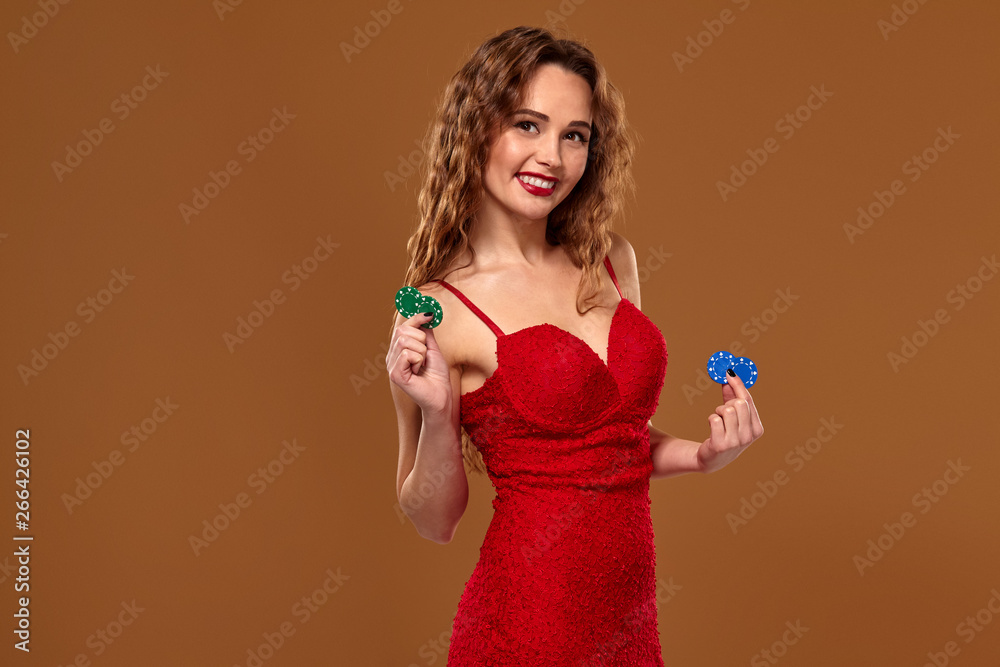 Casino concept. Portrait of young brown-haired caucasian woman, playing in casino. Roulette, poker chips, cards, wheel, brown background Casino concept. Portrait of young brown-haired caucasian woman, playing in casino. Roulette, poker chips, cards, wheel, brown background