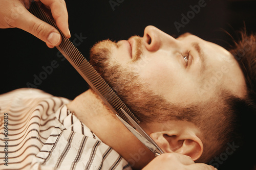 Trimming man beard with scissors in men Barber shop photo