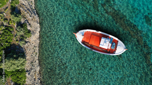 Aerial top view photo of beautiful colourful traditional fishing boat near village of Panormos with turquoise crystal clear sea, island of Tinos , Cyclades, Greece