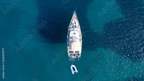 Aerial drone bird's eye top view photo of luxury yacht with wooden deck docked in deep blue waters of Mykonos island, Cyclades, Greece