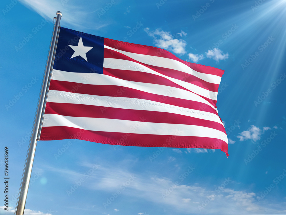 Obraz premium Liberia National Flag Waving on pole against sunny blue sky background. High Definition