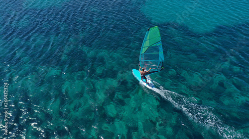 Aerial top view photo of fit man practising wind surfing in exotic open ocean bay with crystal clear emerald sea