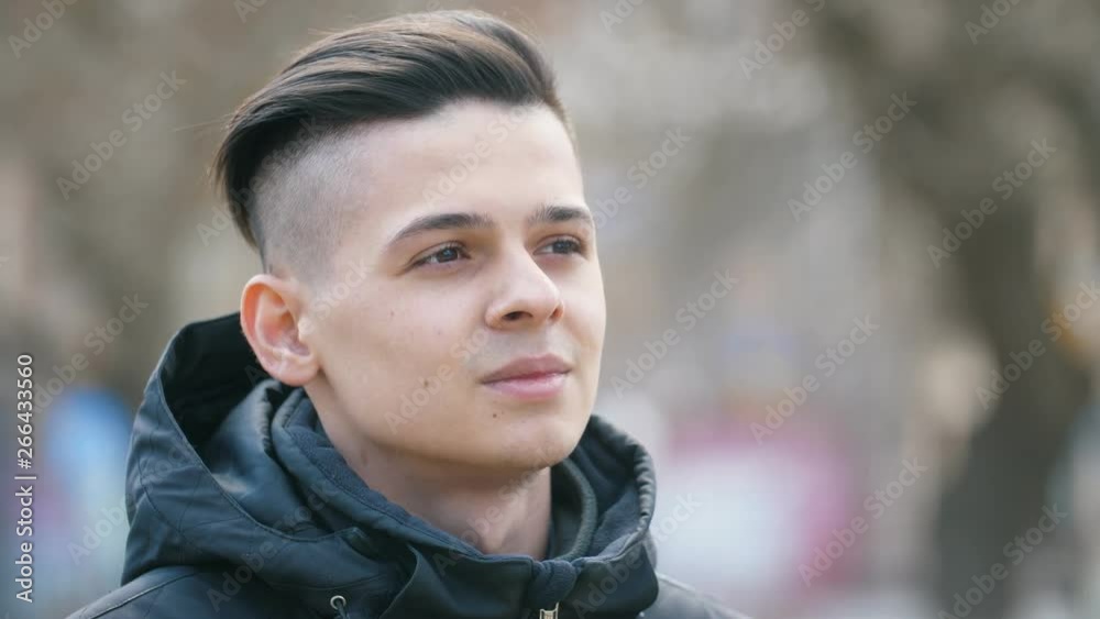Handsome young man looking aside and thinking about future in park in spring Handsome young man looking aside and thinking about future in park in spring