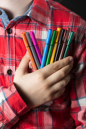 Niño con bolígrafos de colores en la mano.