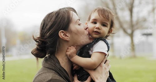 Portrait of a mother kissing her baby girl outdoors
