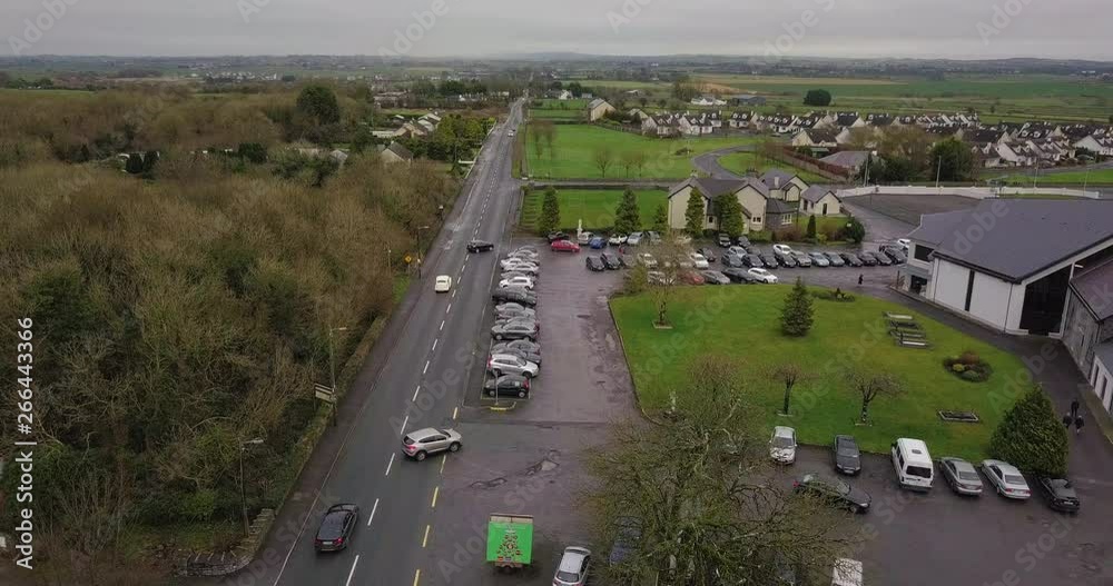 Aerial, car driving down road in Galway, turning into Church Abbey parking lot for wedding celebration Aerial, car driving down road in Galway, turning into Church Abbey parking lot for wedding celebration