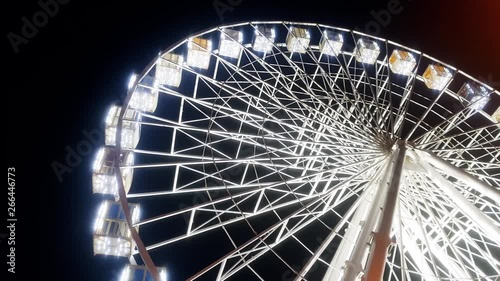 4k video of rotating illuminated ferris wheel in amusement park against night sky photo