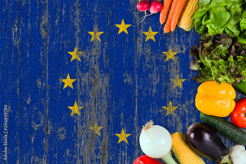 Fototapeta premium Fresh vegetables from European Union on table. Cooking concept on wooden flag background.