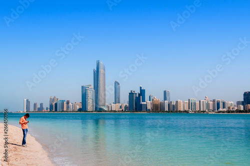 Tourists on beach at marina island with modern Abu Dhabi skyline cityscape © PixHound