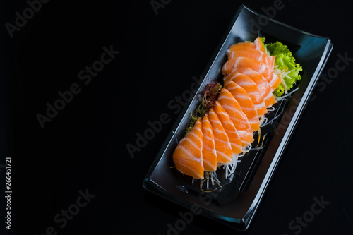 Łososiowy Sashimi na Czarnym Ceramicznym talerzu, czarny tło.