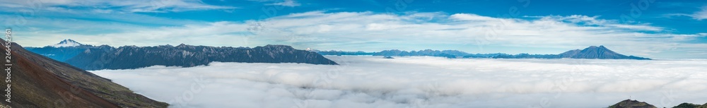 Amazing panoramic view from Osorno Volcano to an awe sea of clouds scenery on an amazing forest with Patagonia mountain range on the far distance dominated by Cerro Tronador mountain on the left