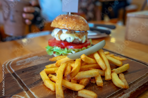 Delicious fresh homemade french fries in front of burger on a wooden table, close-up shooting,Space for text or design