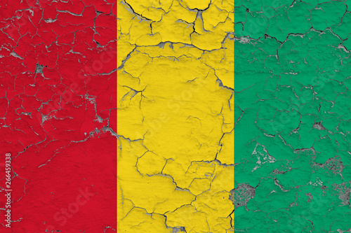 Flag of Guinea painted on cracked dirty wall. National pattern on vintage style surface.