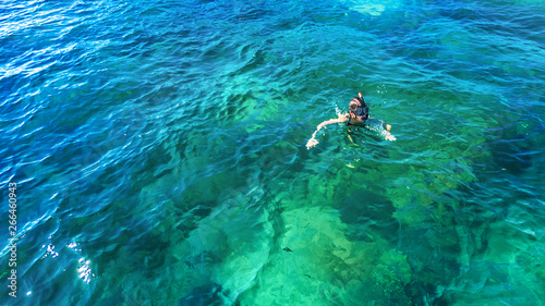 Aerial top view of woman snorkeling from above, girl snorkeler swimming in a clear tropical sea water with corals during summer vacation in Thailand