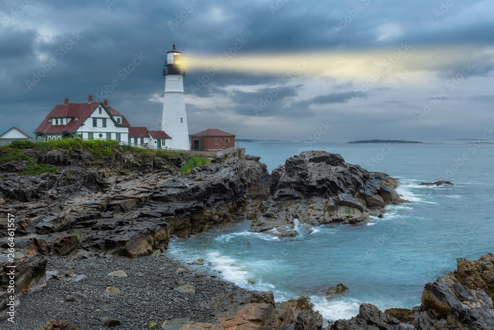 Lighthouse beam light in stormy clouds. Portland Head Light, Maine, USA.