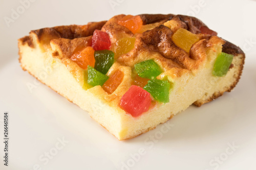 A piece of cottage cheese casserole with candied fruits on a white plate. Close up.