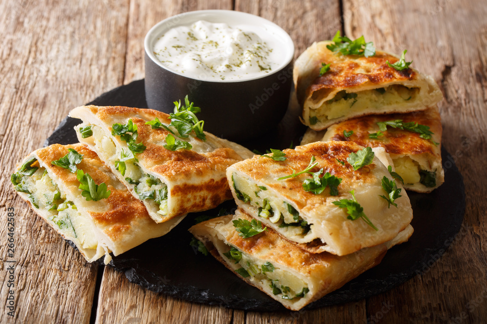 Rustic style afghan fried flatbread bolani stuffed with potatoes, green onions and cilantro close-up. horizontal Rustic style afghan fried flatbread bolani stuffed with potatoes, green onions and cilantro close-up. horizontal