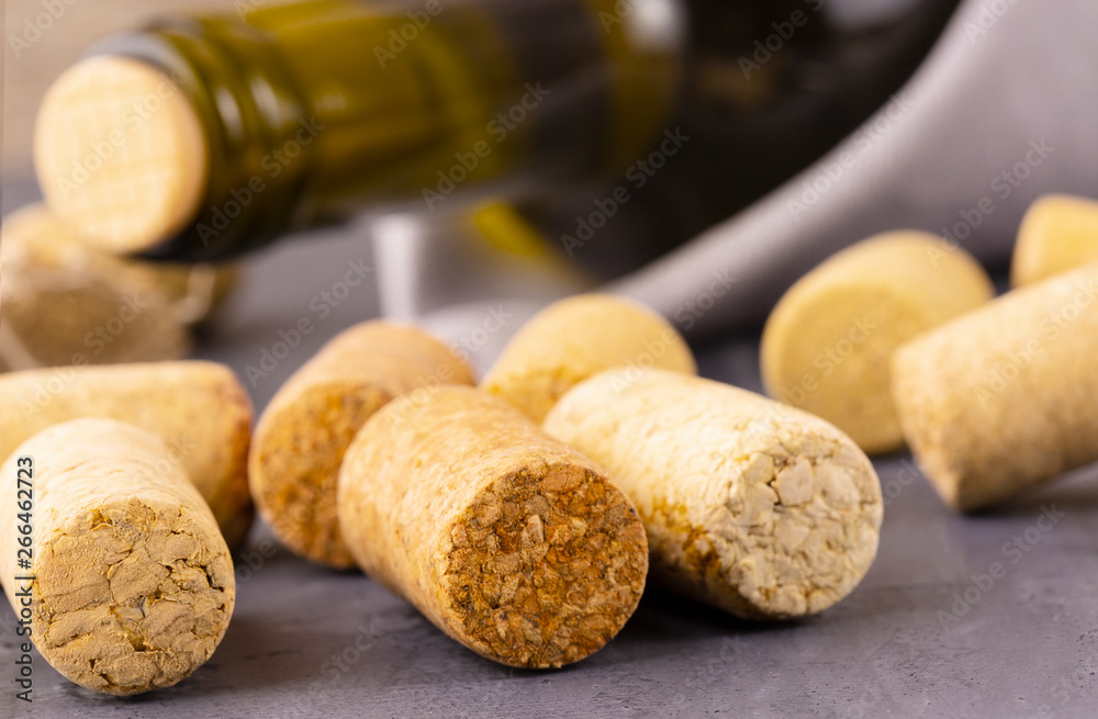 the Glass bottle of wine with corks on wooden table background