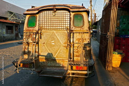 Rear of an old rusty jeepney type of delivery truck, with green windows several padlocks attached to it, parking in the streets of Iloilo, Philippines photo