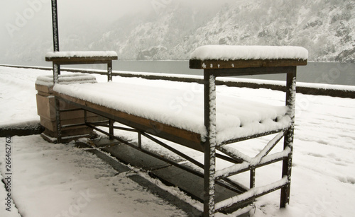 snow-covered bench by the river