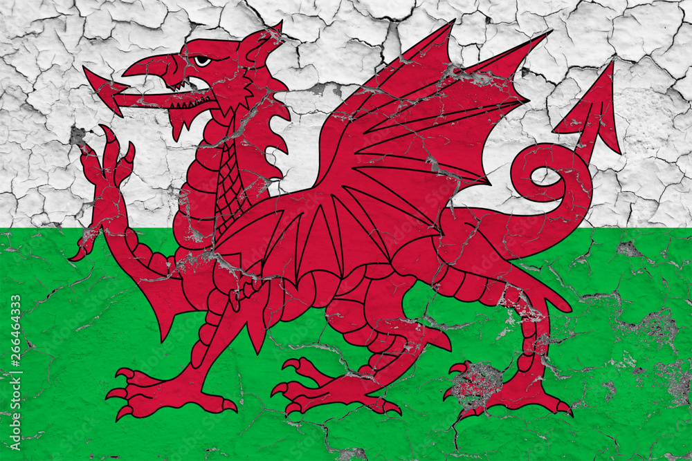 Flag of Wales painted on cracked dirty wall. National pattern on vintage style surface. Flag of Wales painted on cracked dirty wall. National pattern on vintage style surface.