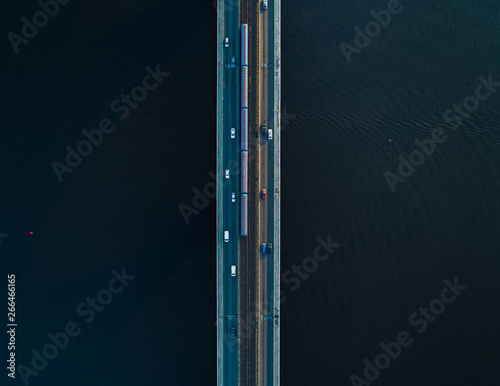 Bridge with two lanes and subway or train rails on a background of dark water. Aerial view