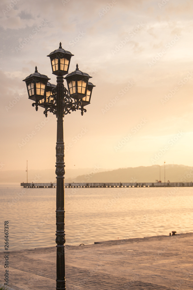 poetic vintage streetlight in a sunset in front of the sea