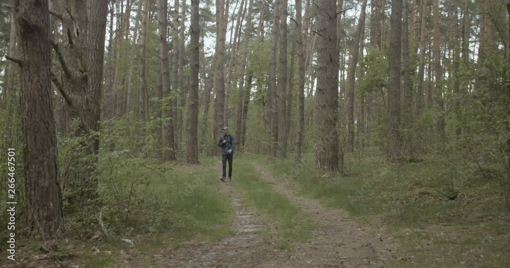 Wide view of young backpacked traveler walking in the forest Wide view of young backpacked traveler walking in the forest